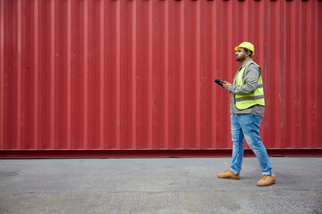 worker or engineer walking forward and working on tablet in containers warehouse storage