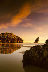 Splendid sunrise in reddish tones among the rocks of Buelna beach, Asturias III