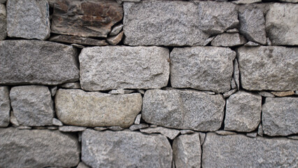 An abstract depiction of a Cyclopean wall, replicating the texture and set against the backdrop of an old castle's rocky stones. The wall itself has a texture that combines rough-hewn rock.