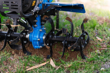 A small manual hand tractor plows the soil. The concept of agriculture and industry