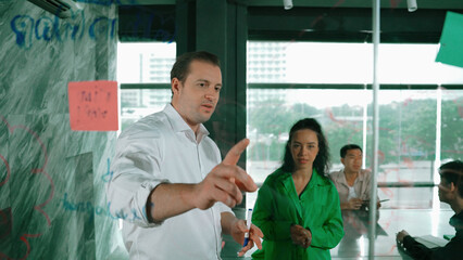 Skilled businessman presents marketing idea to project manager by using colorful sticky notes at...