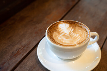Hot coffee latte with latte art milk foam in cup mug on wood desk on top view. As breakfast In a coffee shop at the cafe,during business work concept,vintage style