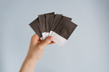 Disposable bags with cosmetics in a woman's hand on a blue background