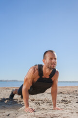 Fototapeta na wymiar young man does exercises on the beach outdoors