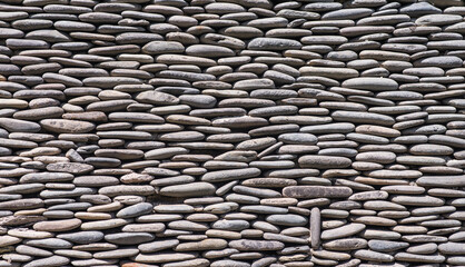 Gray round river pebbles stone wall background