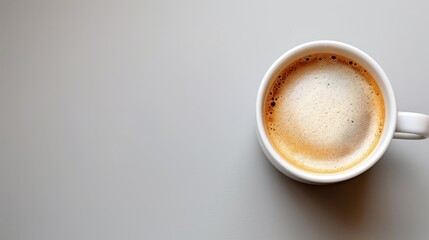   A tight shot of a coffee cup on a table, equipped with a spoon and spoon rest adjacent