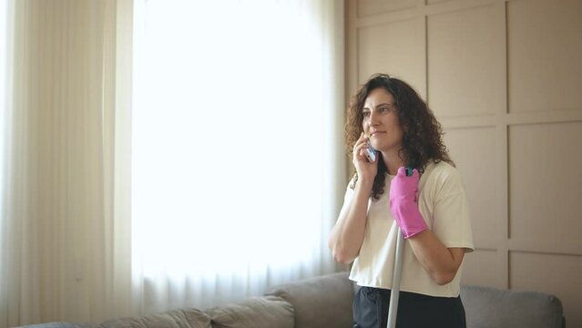 Ethnic biracial housewife do housework housekeeping work talking mobile phone call, multitask
