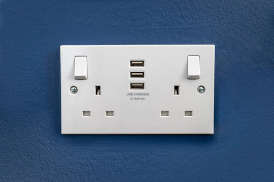 UK Double Plug Socket with USB Chargers 3 Pin on a Blue textured wall