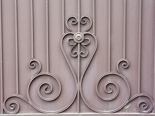 A beautiful forged element of a brown solid fence.