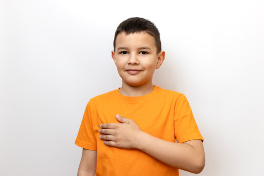 The boy stands and puts his hand to his heart. Sincere children's emotions.