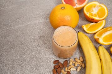 Fruit nut smoothie in a glass on a stone background, place for text