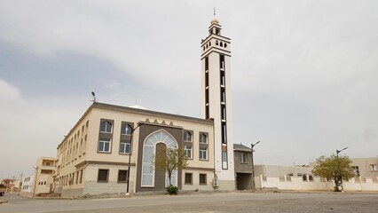 Fototapeta premium Historic mosque with tower and clock in a Algerian city, featuring ancient architecture