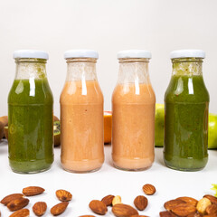 Different vegetable and fruit smoothies in glass bottles on white background