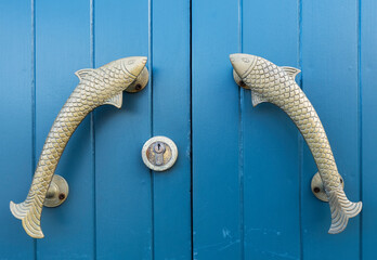 Blue door with lock and two fish as handles
