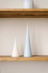 Blue and white taper candle on a wooden shelf in a Scandinavian minimalist style living room