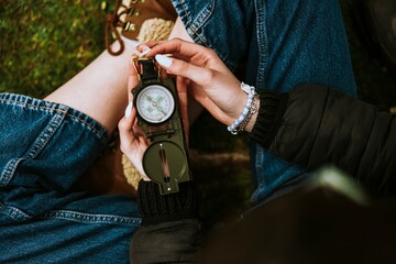 Woman's hands holding compass, camping equipment