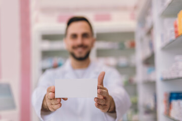 Male pharmacist holding up a box of medication in the pharmacy.
