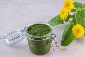 Creamy dandelion greens pesto in jar on a white background. Appetizer, condiment or topping....