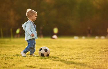 Playing with soccer ball. Cute happy little boy is on the field outdoors