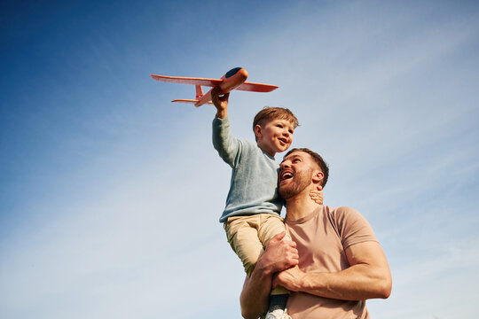 Father is holding son that playing with toy plane