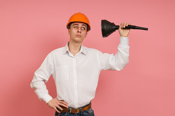 young builder looks with interest inside black funnels on a pink background