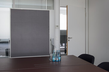 A black pinboard close-up in a conference room, opened door, dark brown table