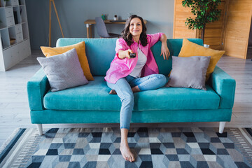 Obraz premium Photo of cheerful adorable senior woman sitting comfy sofa watching tv set enjoying weekend indoors