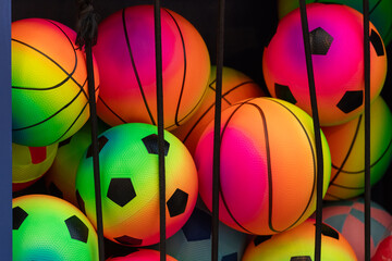 A bin of colorful toy soccer and basketballs in a wire bin for sale. The balls are pink, purple,...