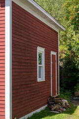 The exterior corner view of a vintage red storage building. The old wooden structure has wood...