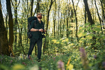 Tourist with binoculars. Bearded man is in the forest at daytime