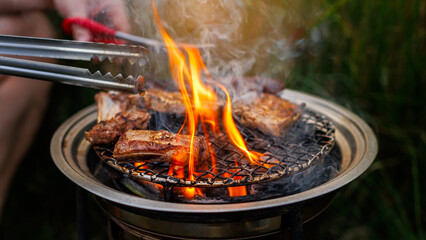 skewers meat ribs and sausage barbecue grilled on the grill with charcoal flames in camping party...