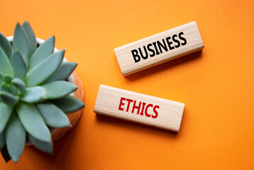 Business ethics symbol. Concept word Business ethics on wooden blocks. Beautiful orange background...