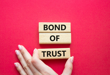 Bond of trust symbol. Wooden blocks with words Bond of trust. Beautiful red background. Businessman...