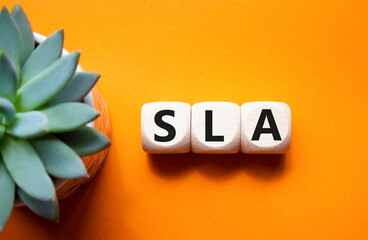 SLA - Service Level Agreement. Wooden cubes with word SLA. Beautiful orange background with...