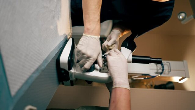 vertical video in a veterinary clinic on the veterinary table doctors are setting up microscope