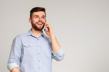 Great news. Cheerful man using his phone and widely smiling on studio background, panorama, free...