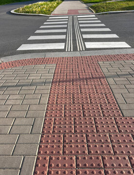 Marked barrier-free transition. Urban paved sidewalk and roadway with markings for handicapped pedestrians.
