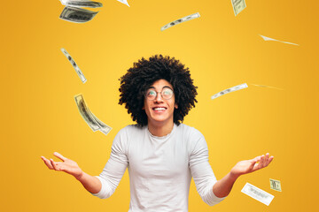 Unexpectable fortune. Excited black millennial guy enjoying rain of money, orange studio background