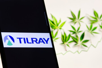 Naklejka premium Tilray company logo on screen of smartphone against blurred background of cannabis and chart.