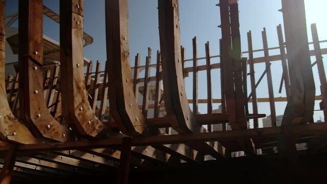 Craft shipyard. Hull of yacht at wharf under construction. Low angle view of yacht frame on a stock. Wooden vessel being constructed