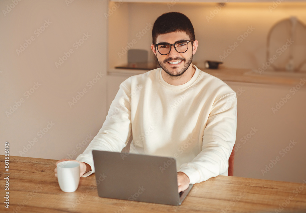 Aufkleber a man is seated at a table, focusing on his laptop screen. he appears engaged in work or study, with