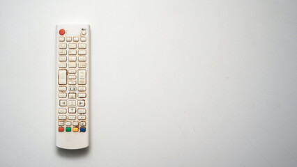 Old white TV remote control with multicolored buttons lies isolated on white background. Visible...