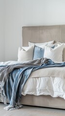 Modern bedroom interior with beige headboard, white and blue pillows, and a blue textured throw.