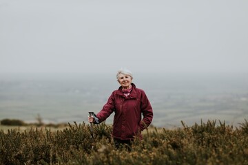 Naklejka na ściany i meble Senior woman trekking through field