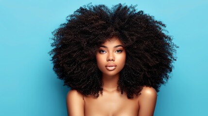   A tight shot of a woman wearing an expansive afro against a backdrop of a blue wall