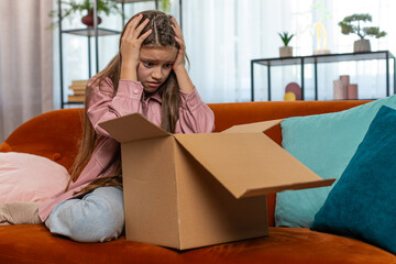 Angry dissatisfied shopper child girl unpacking parcel feeling upset and confused with wrong...