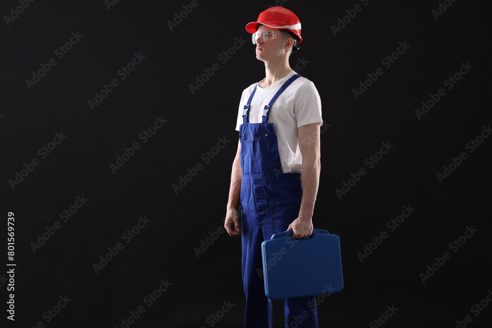 Wall mural Professional repairman with tool box on black background. Space for text