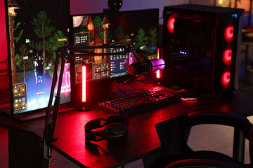 Playing video games. Modern computer, microphone and headphones on table indoors