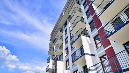 A view at a detail of a modern white apartment building with blue sky background.