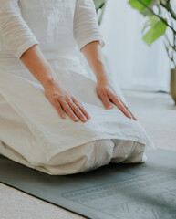 a woman wearing white clothes sitting in Vajrasana (Thunderbolt Pose), doing yoga at home, calm...